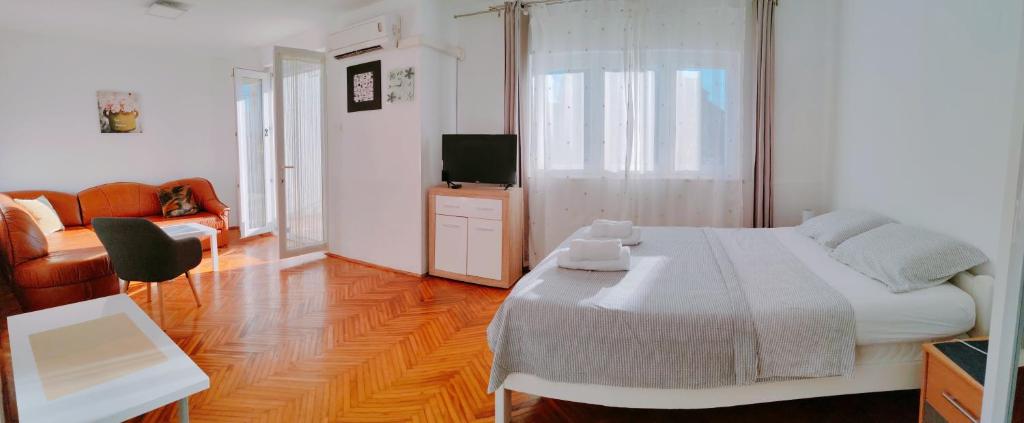 a bedroom with a bed and a couch and a television at Apartmani Bojana in Rovinj