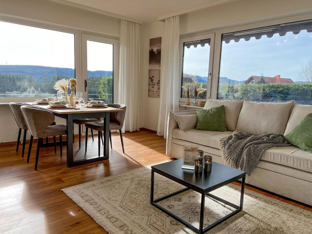 uma sala de estar com um sofá branco e uma mesa em Feldbergblick mit Schwimmbad und Sauna em Lenzkirch