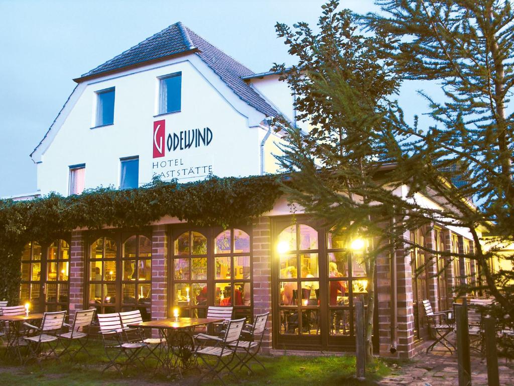 a hotel with tables and chairs in front of a building at Hotel GODEWIND in Hiddensee