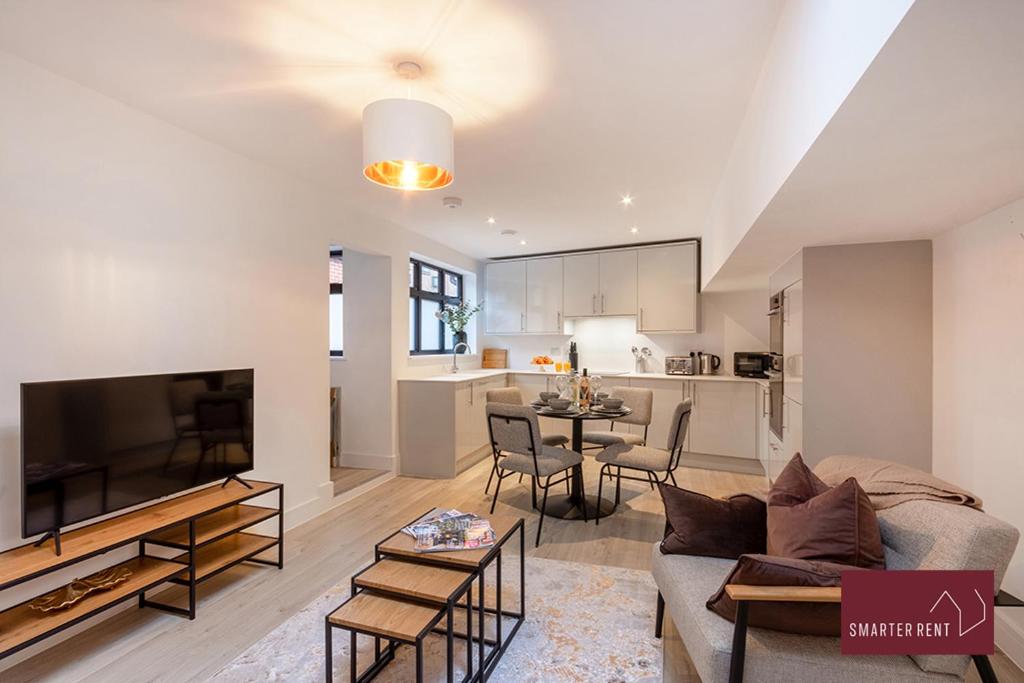 ein Wohnzimmer mit einem Sofa und einem TV sowie eine Küche in der Unterkunft Modern 3 Bedroom Apartment - Wokingham in Wokingham