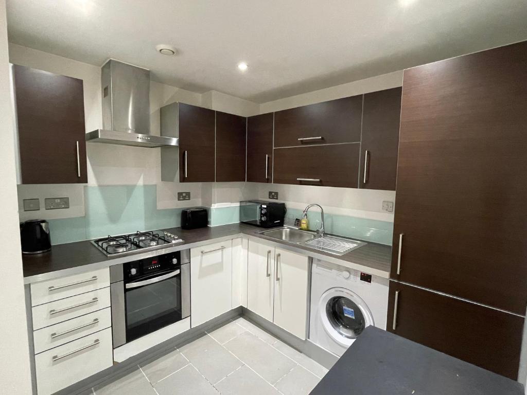 uma cozinha com armários brancos e uma máquina de lavar e secar roupa em London 2Bedrooms 2Bathrooms, Balcony, Parking, Lovely South Woodford em Londres