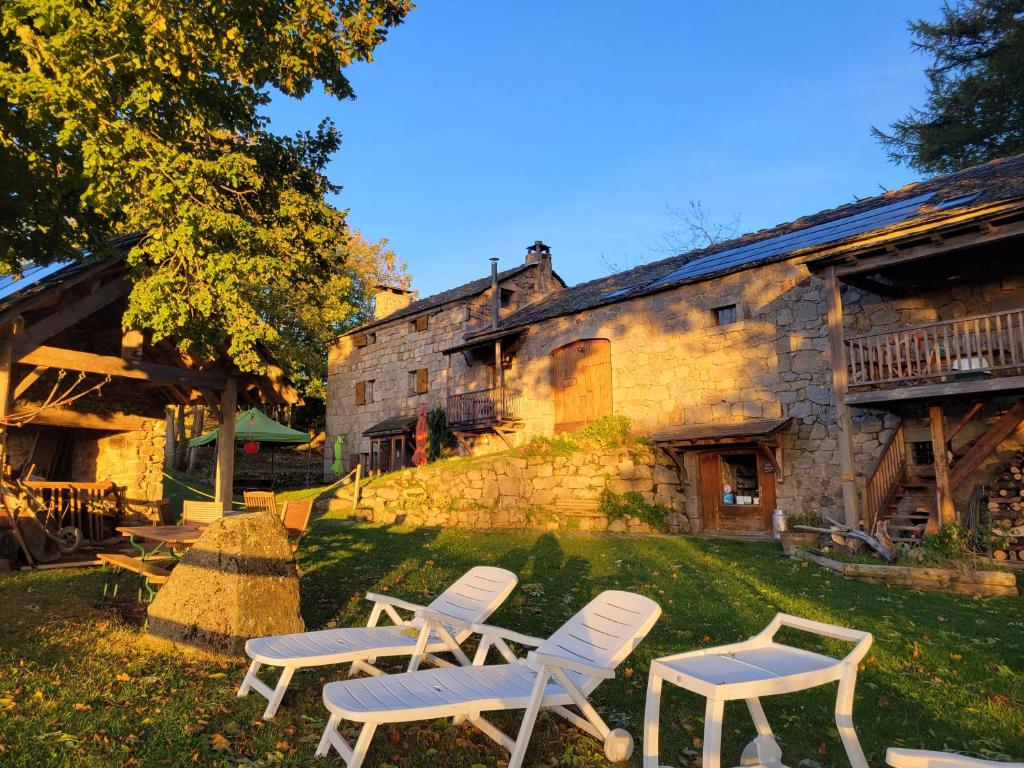 un grupo de sillas frente a un edificio en Magnifique gite 14 personnes en bord de lac, en Devesset