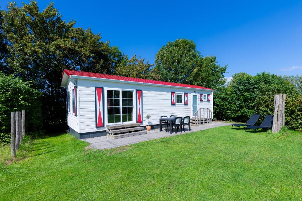 een kleine witte hut met een picknicktafel en stoelen bij Chalet Plantlust in Veere