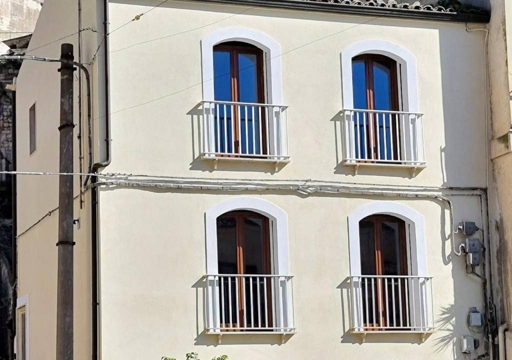 ein weißes Gebäude mit Fenstern und Balkonen darauf in der Unterkunft B&B da Francesco in Modica