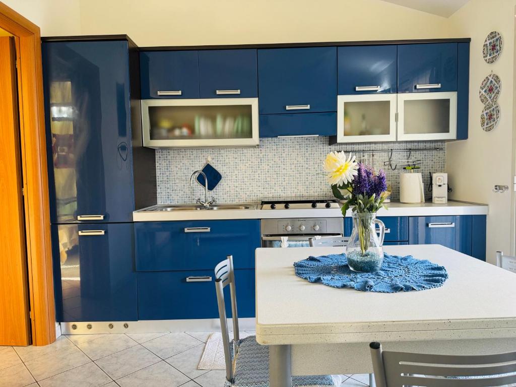 a kitchen with blue cabinets and a table with flowers at Casa Orchidea Altera in Marzamemi