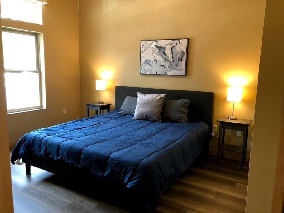 a bedroom with a large blue bed with two lamps at Cannery Square Apartment 104 in Sun Prairie