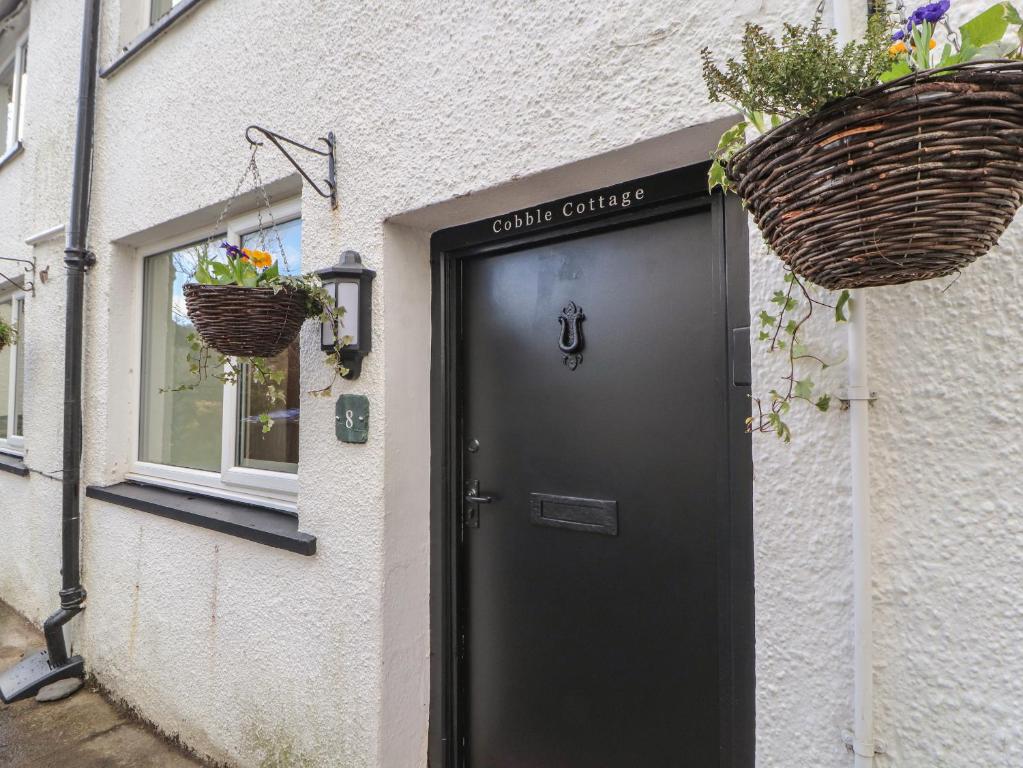 een zwarte deur op een wit gebouw met twee manden bij Cobble Cottage in Keswick