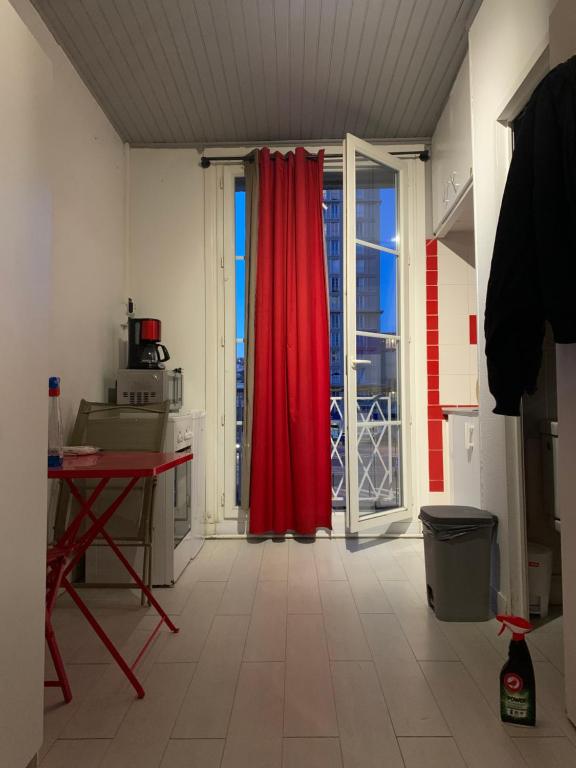 een keuken met een rood gordijn en een rode tafel bij STUDIO LE HAVRE PLAGE in Le Havre