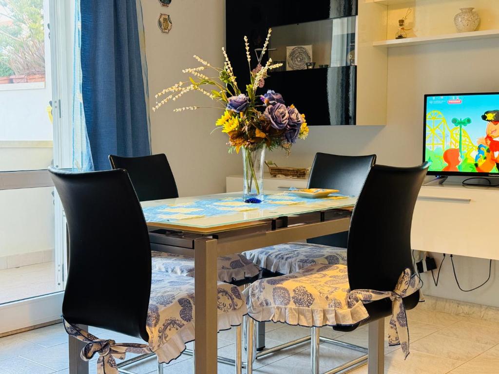 マルツァメミにあるCasa vacanza "Orchidea"のダイニングルームテーブル(椅子付)、花瓶