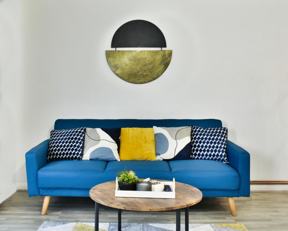 ein blaues Sofa im Wohnzimmer mit einem Tisch in der Unterkunft Lovely flat near University of Reading in Reading