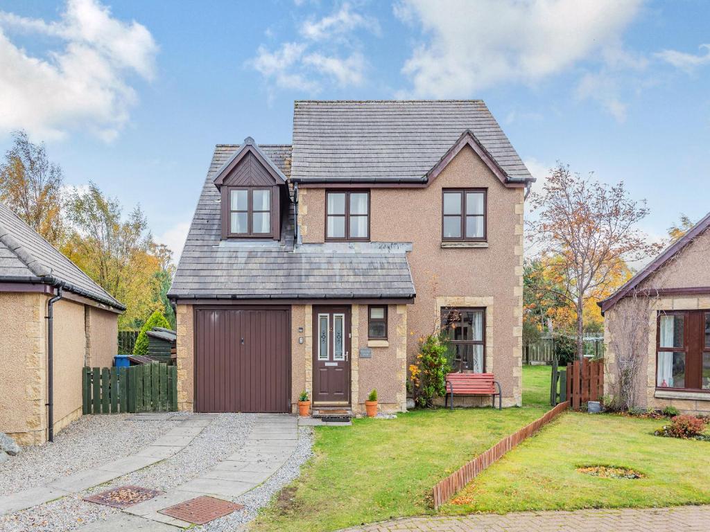 a brick house with a garage in a yard at Cairnie View in Aviemore