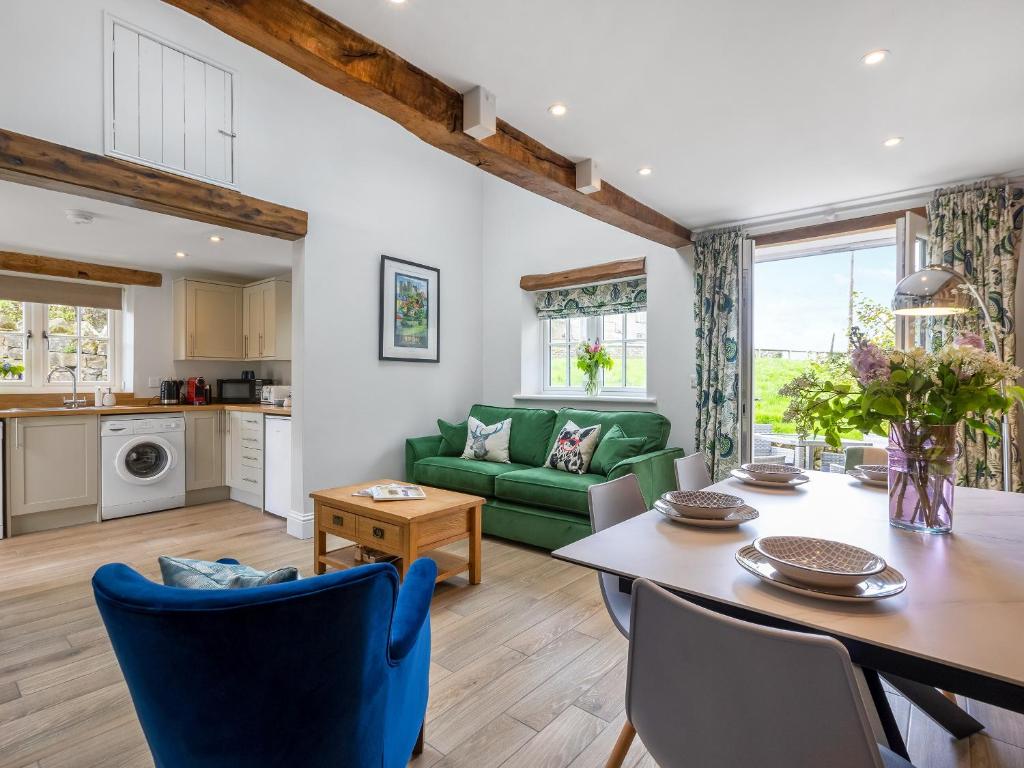 ein Wohnzimmer mit einem Tisch und einem grünen Sofa in der Unterkunft Cherry Cottage - Uk46357 in Grantley