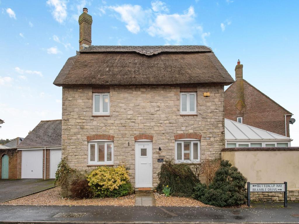 an old brick house with a thatched roof at The Roddy House in West Bay