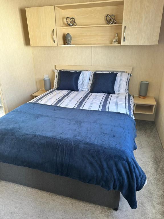 1 dormitorio con 1 cama grande y edredón azul en Camber Vacations, en Camber
