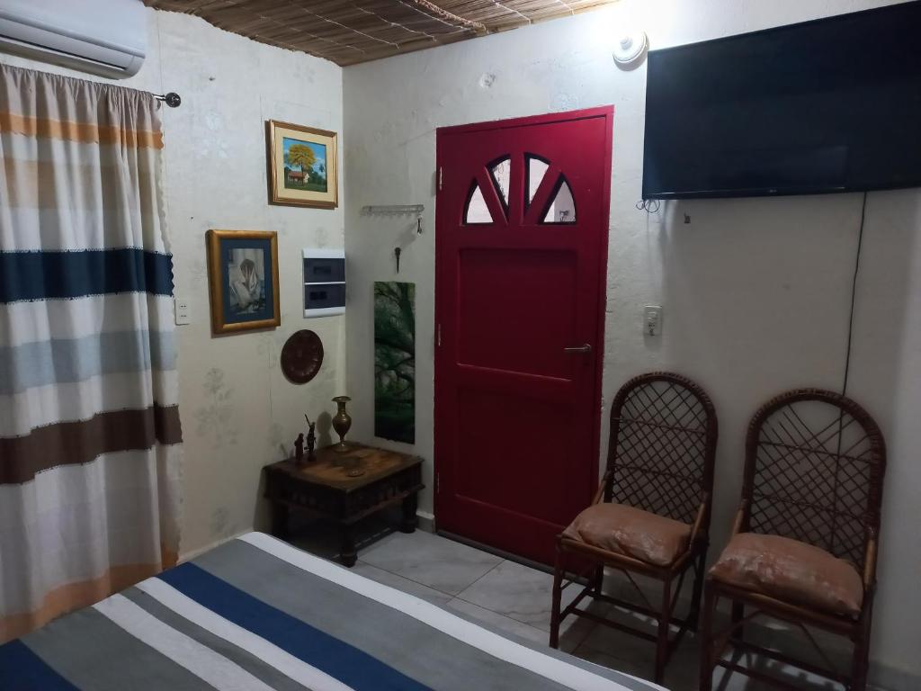 1 dormitorio con puerta roja y 2 sillas en La Petite Maison, en Asunción