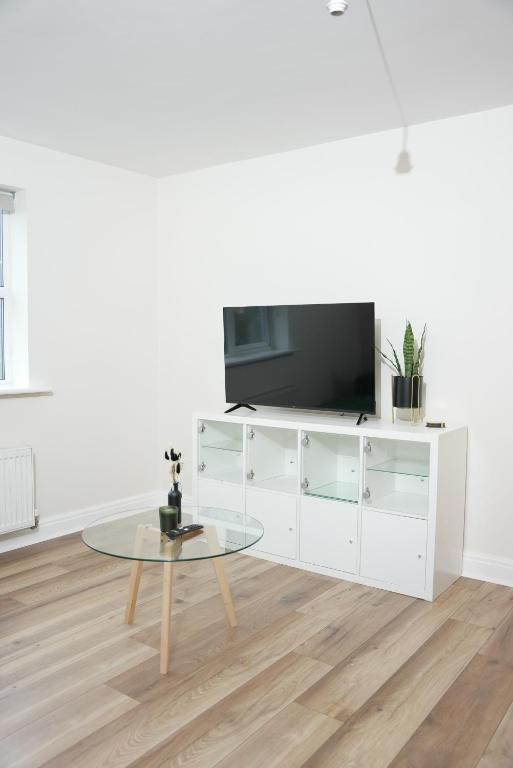 uma sala de estar branca com uma televisão e uma mesa em Stylish Pride Park DERBY Apartment - Free WIFI, Parking em Derby