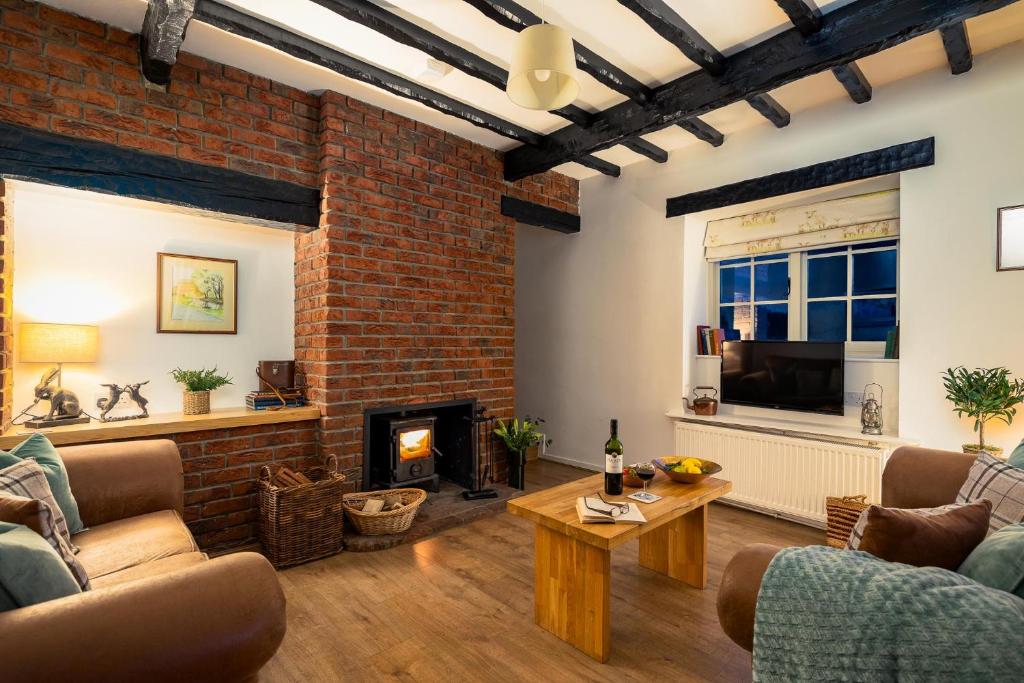 a living room with a fireplace and a brick wall at Yew Tree Cottage in Ayton