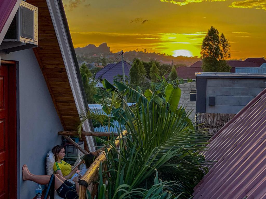 a woman sitting on the balcony of a house with a sunset at Home Villa Arusha in Arusha