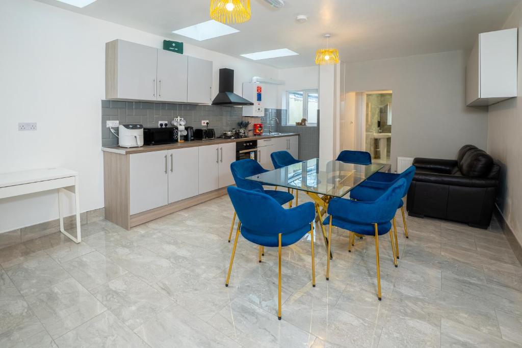 cocina y comedor con mesa de cristal y sillas azules en Kunda House Coventry Road en Birmingham