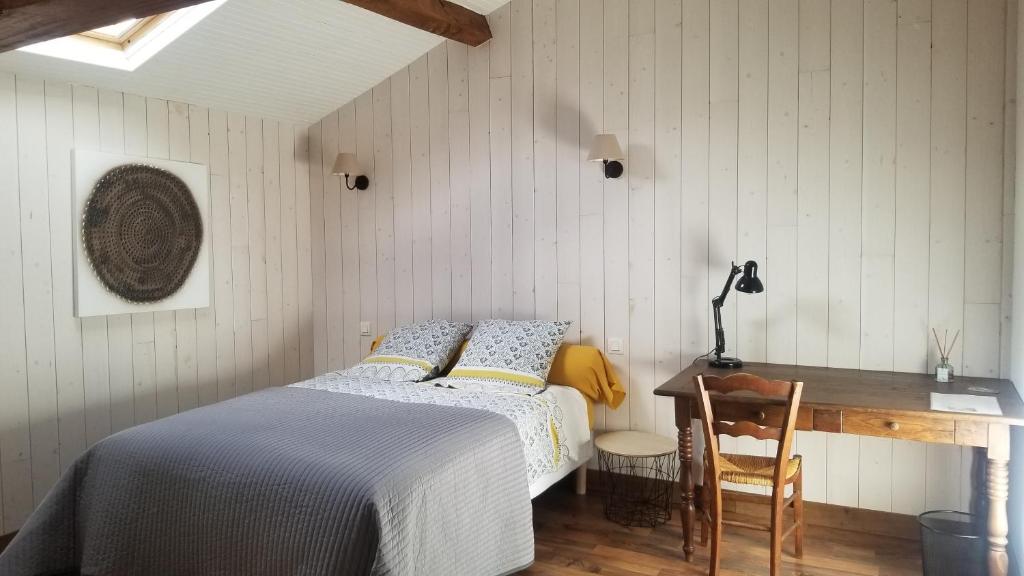 a bedroom with a bed and a desk and a table at Chambres et gîte dans un lieu calme et champêtre in Gourgé
