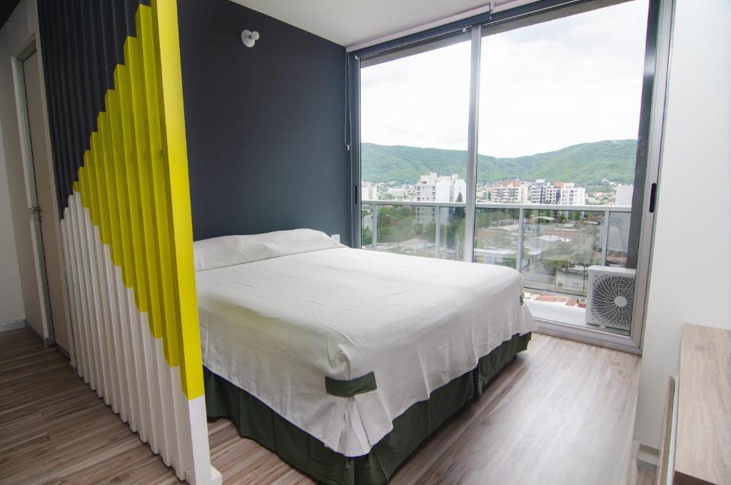 una camera da letto con letto con testiera gialla e ampia finestra di DA DFC a Salta