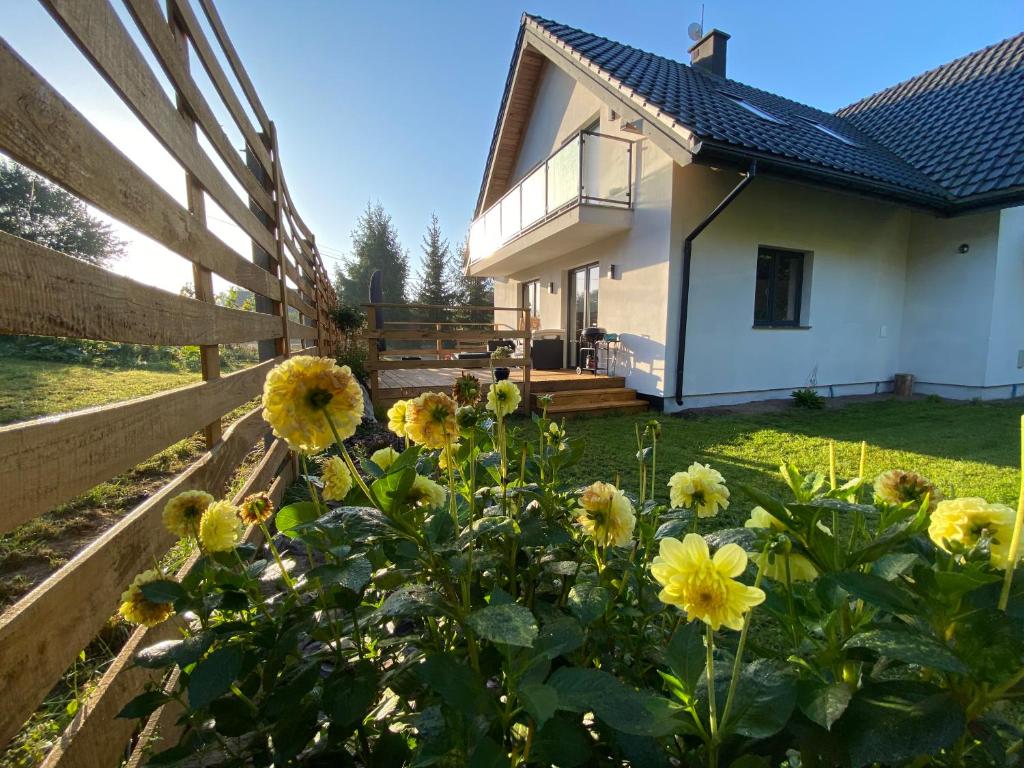 a house with a fence and a garden with yellow flowers at Apartament Masuria SPA Renata Rosłoń in Świętajno