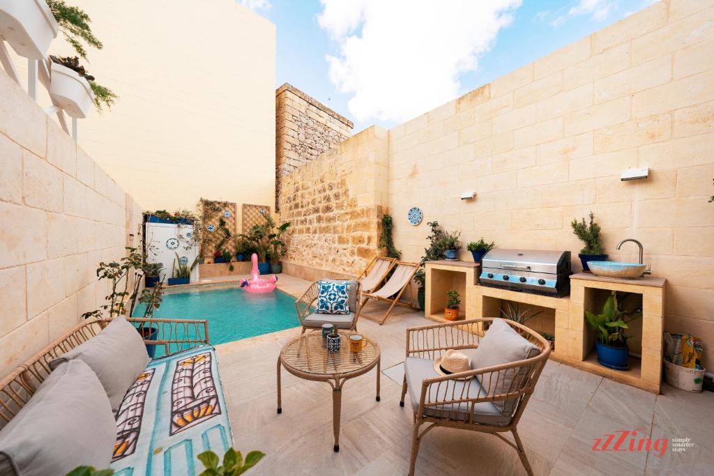 un patio con piscina, sillas y mesa en A remarkable Eco Home in Gozo, en Nadur