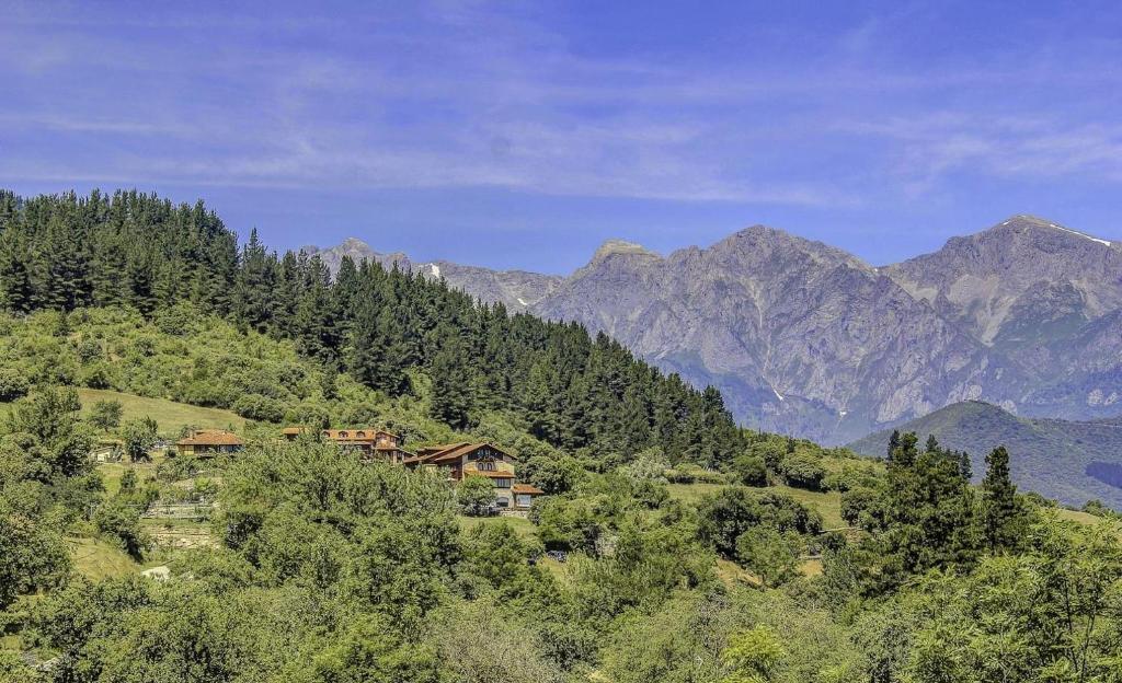 a house on a hill with mountains in the background at Apartamentos Calm & Nature en Liebana in Cabezón de Liébana