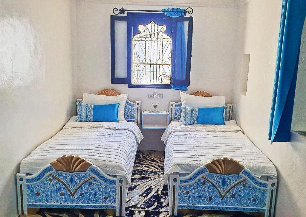 舍夫沙萬的住宿－Dar La Aicha，蓝色和白色的客房内的两张床