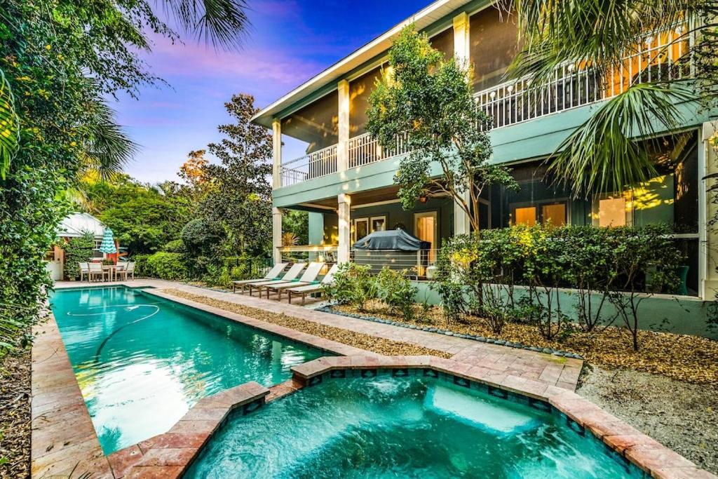 a swimming pool in front of a house at Casa Mariposa - Luxury Butterfly Garden Steps to Pine Ave PoolSpa Bikes 4 Houses to Beach in Anna Maria