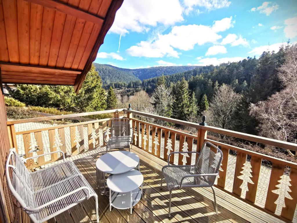 a deck with chairs and a table and a view at Chalet Pura Vida - En pleine nature, tout confort in Le Valtin