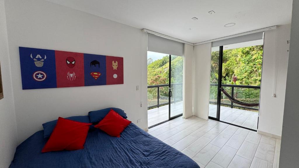 sypialnia z łóżkiem z czerwonymi poduszkami i balkonem w obiekcie Casa Hotel GAIA Espetacular Finca w mieście Manizales