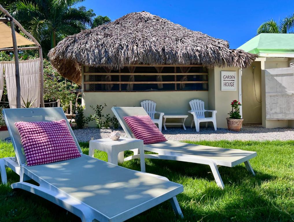 two chairs and a table and chairs in front of a hut at Garden house by Petraki in Las Galeras