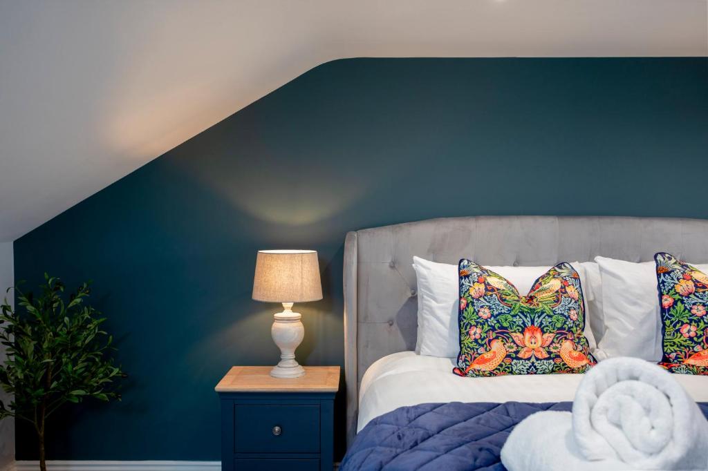 a bedroom with a bed with a blue wall at Kist Accommodates - Belmont Dene in Knaresborough