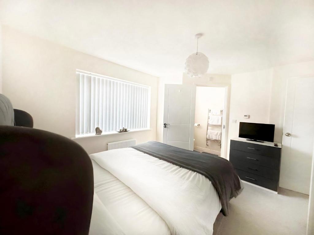 a white bedroom with a bed and a television at Ensuite Room with free parking 