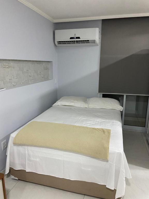 a bedroom with a white bed and a air conditioner at Flat Completo in Vila Velha