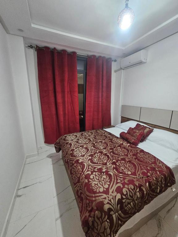 1 dormitorio con cortinas rojas y 1 cama grande en Appartement moderne près de la corniche, en Nador