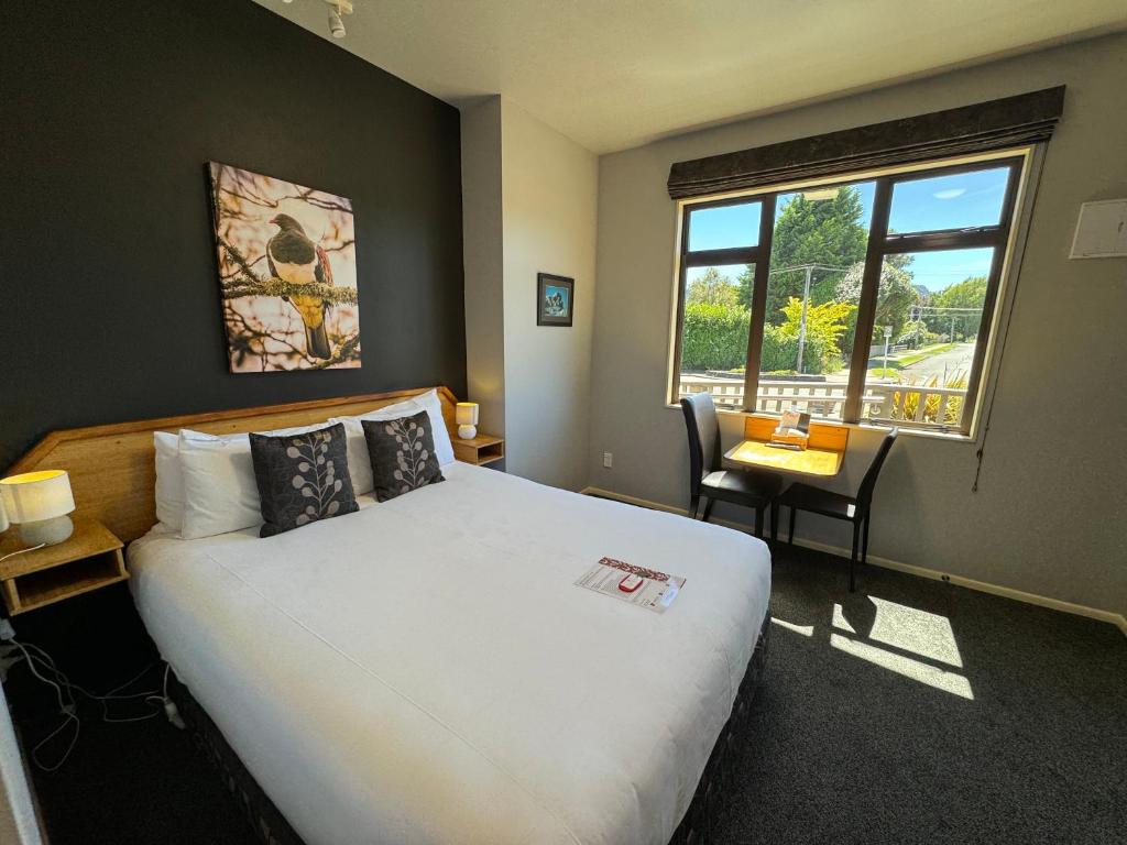 a bedroom with a bed and a desk and a window at Snowhaven in Ohakune