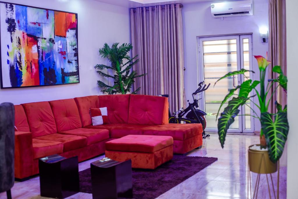 a living room with a red couch and a plant at Ìtùnú at Molara's Villa in Abeokuta