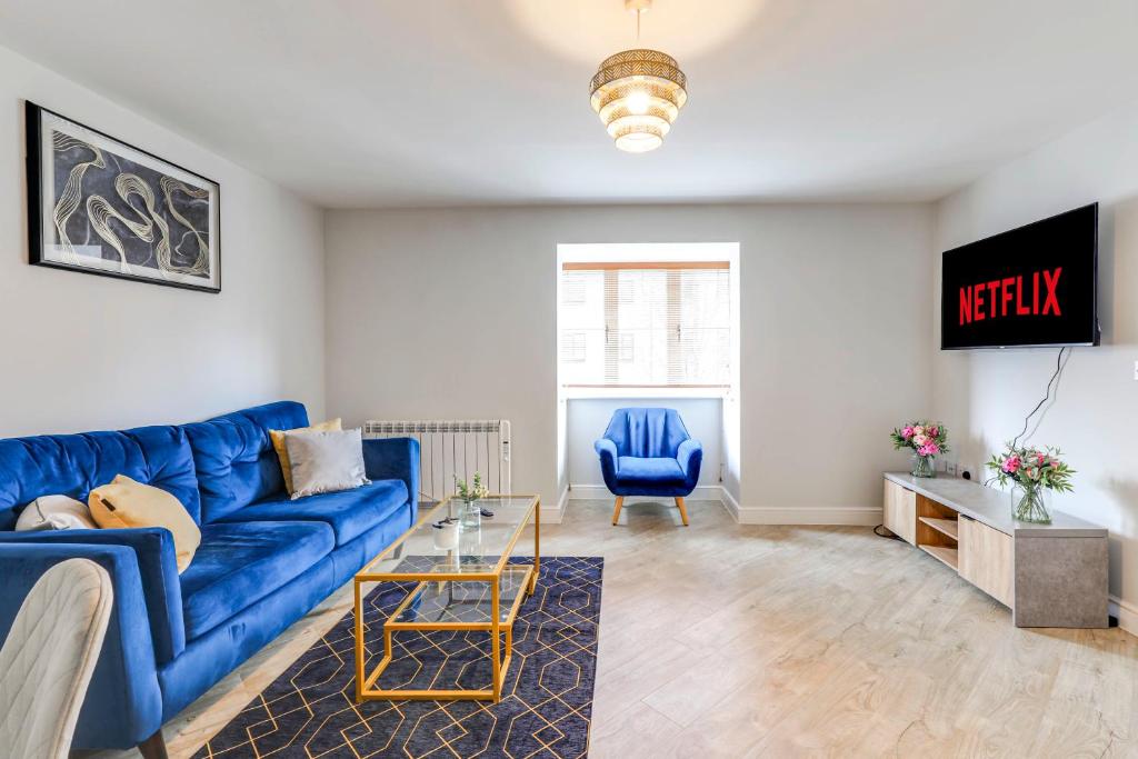 a living room with a blue couch and a table at Welwyn Garden City Apartment by Mantis in Welwyn Garden City