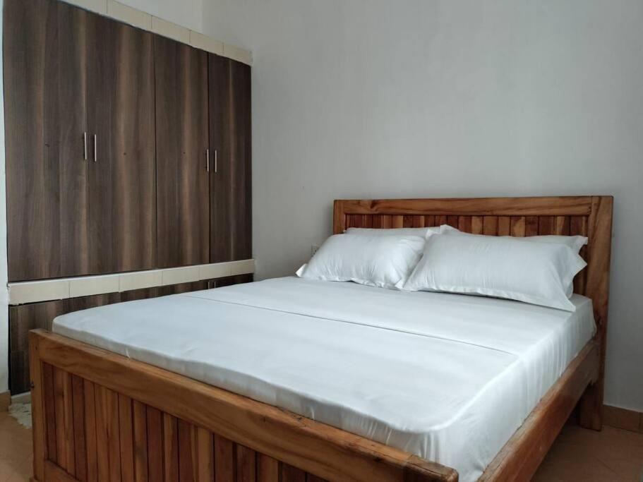 a bedroom with a large bed with a wooden cabinet at Stay with Adhiambo in Kilifi