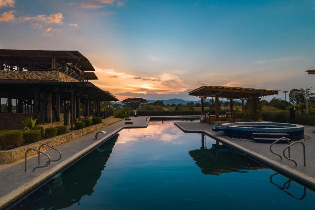 einen Pool in einem Resort mit Sonnenuntergang im Hintergrund in der Unterkunft Hotel El Cielo en la Tierra in Alcalá