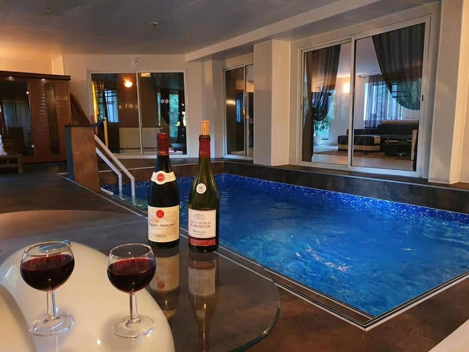 two bottles of wine on a table next to a swimming pool at Au Bois de Massier - Chambre d'hôtes in Vienne