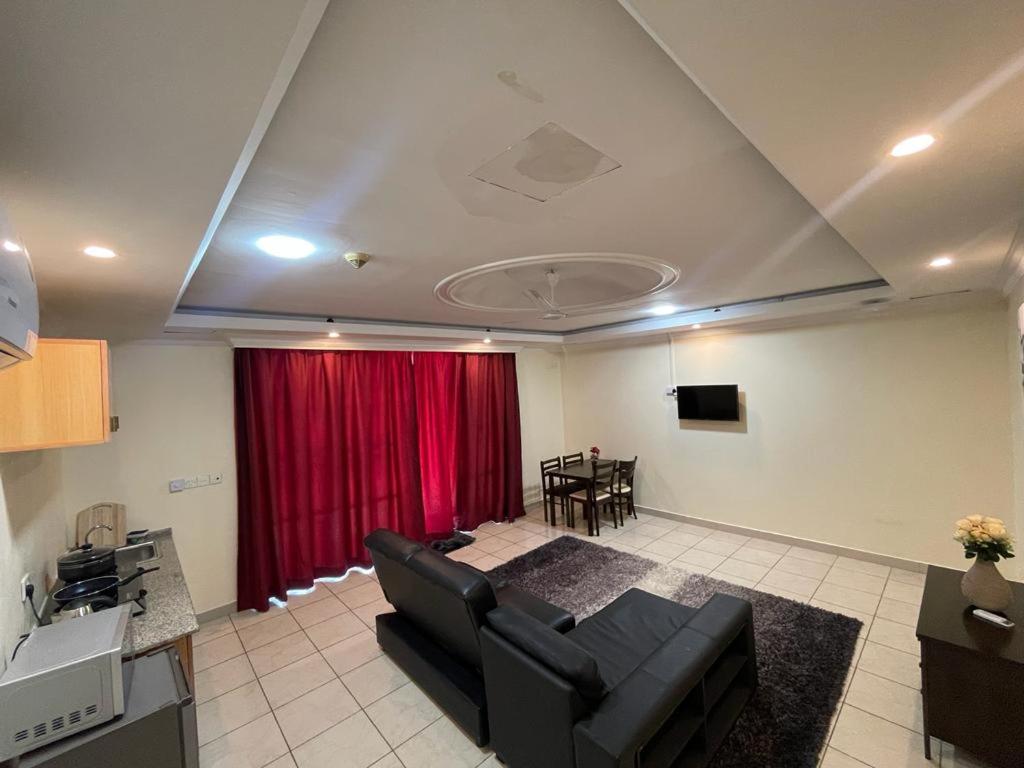 een woonkamer met een bank en een rood gordijn bij Kolo's Mayfair private apartments in Dar es Salaam