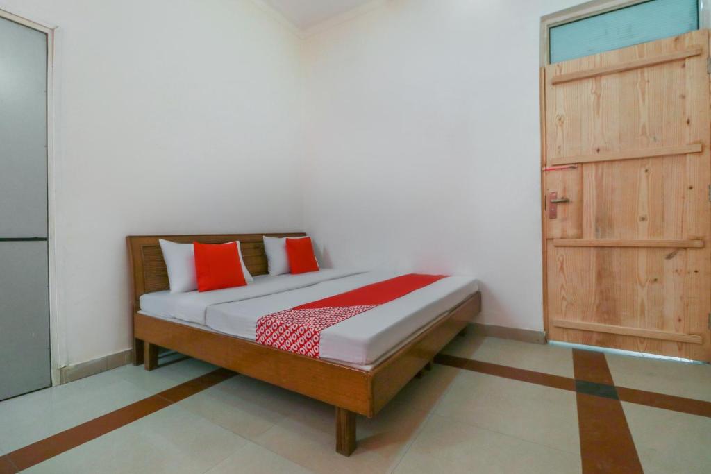 a bedroom with a bed and a wooden door at OYO Flagship Mg Mehak Garden in Darbi