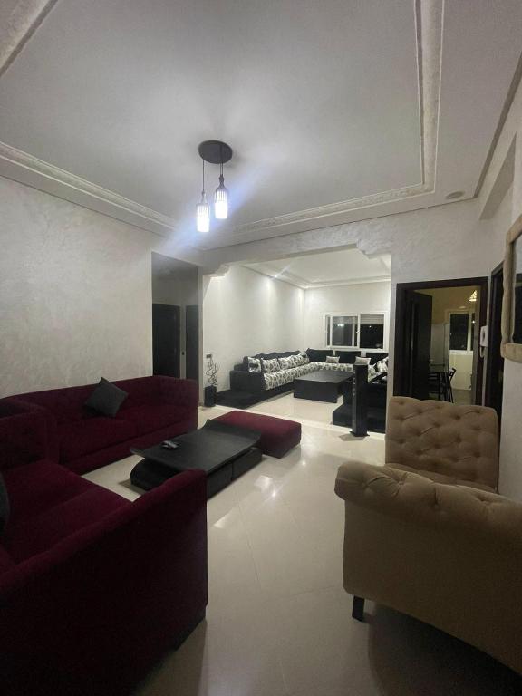 uma grande sala de estar com sofás vermelhos e cadeiras em appartement moderne em Minaret de Mansuria