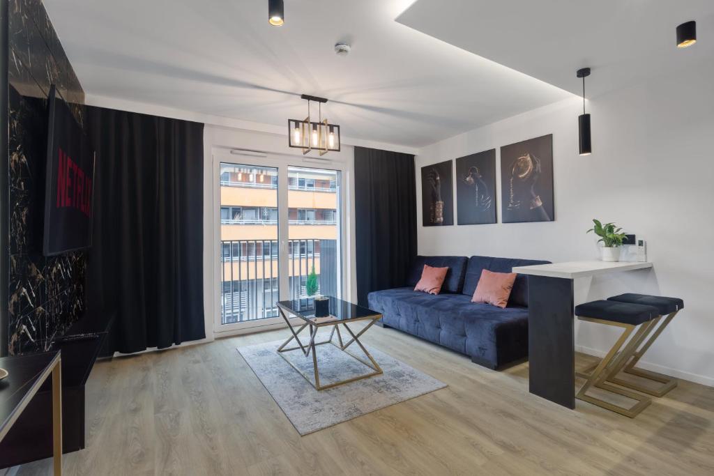 a living room with a blue couch and a table at Apartament Park Partynice in Wrocław