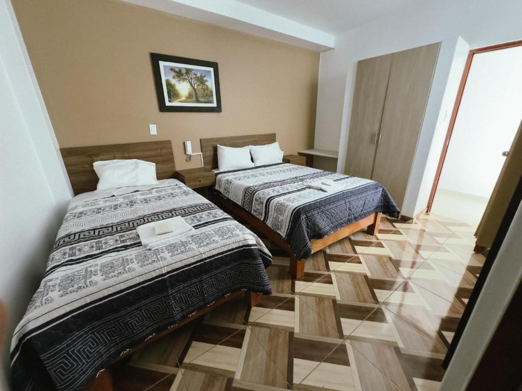 a hotel room with two beds and a tile floor at HOTEL NILA in Cajamarca