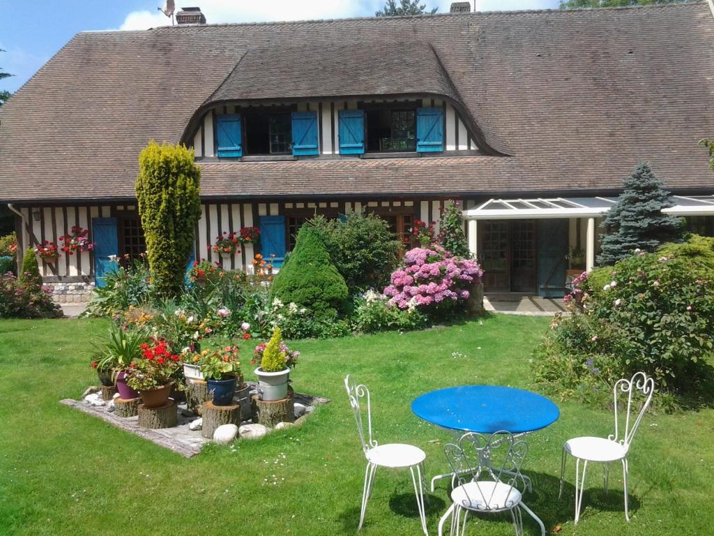 a house with a blue table and chairs in the yard at Chez Catherine - Chaumière Normande in Theuville-aux-Maillots