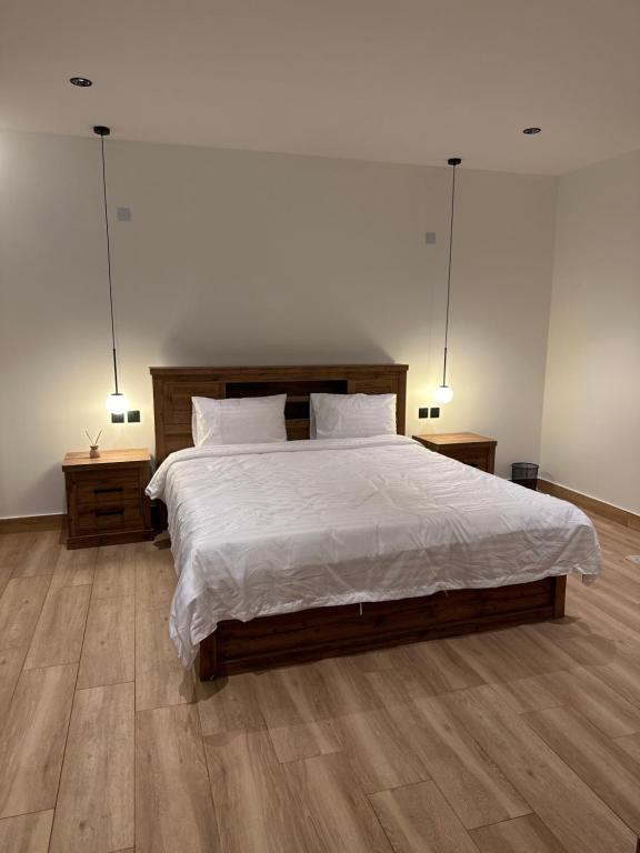1 dormitorio con 1 cama grande y 2 mesitas de noche en شاليه الجبل ( 2 ), en Ḑubā
